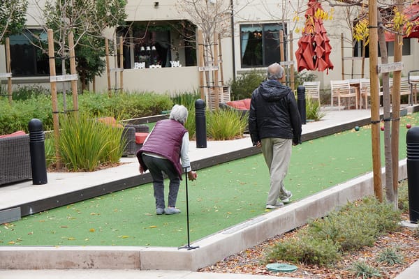Residents enjoying outdoor bowling on a putting green
