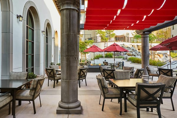 Outdoor seating area with shaded tables and chairs