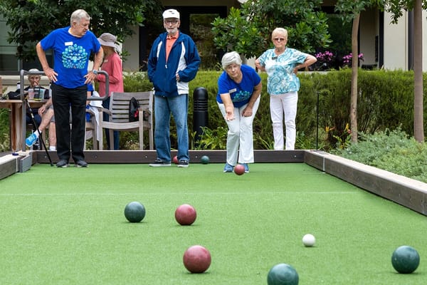Residents playing bocce ball outdoors in a garden