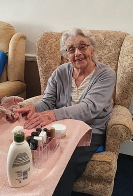 Elderly resident enjoying a manicure in a cozy chair