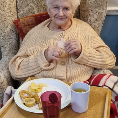 Elderly woman enjoying snacks in a cozy chair