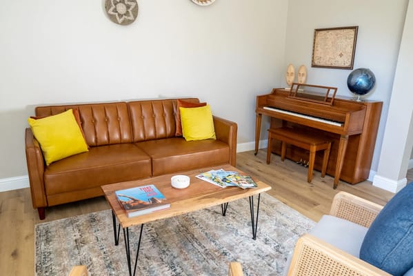 A cozy common area with a sofa and piano