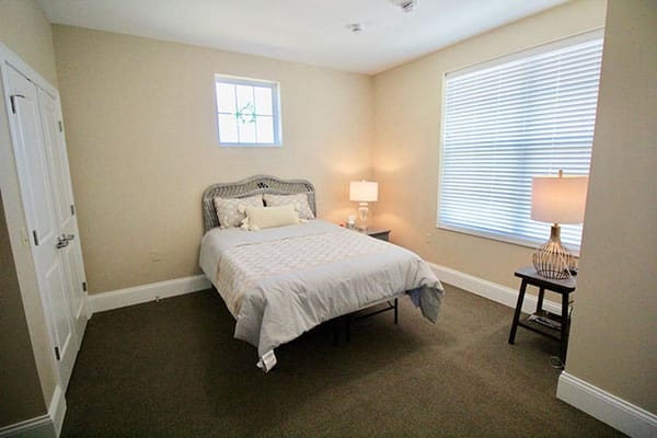Bright private resident room with a bed and lamp