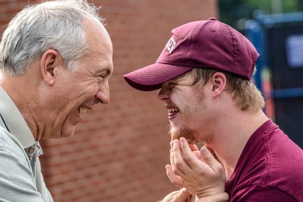 Two men laughing during an outdoor interaction