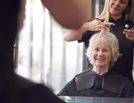 A stylist cutting the hair of a smiling senior woman