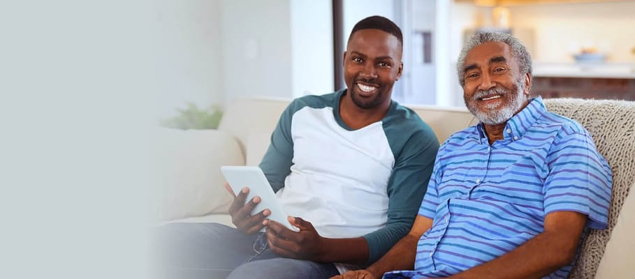 A smiling older man sitting with a younger man in a cozy living room