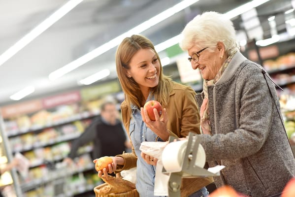 Senior resident shopping for groceries with a staff member