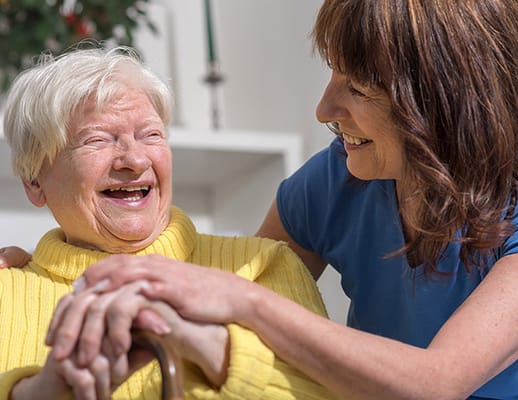 A caregiver and an elderly resident sharing a joyful moment