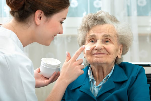 Caregiver applying moisturizer to a resident's face