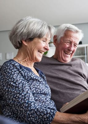 Two smiling seniors reading together