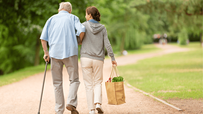 A caregiver assisting a senior in a park