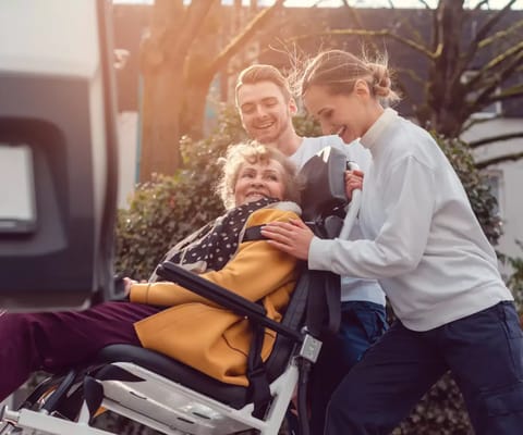 Care staff assisting a resident in a wheelchair outdoors
