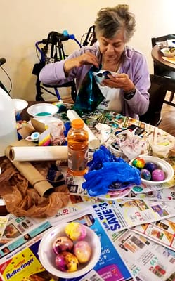 Resident engaged in decorating Easter eggs at a table
