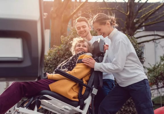 Care staff assisting a smiling resident outdoors