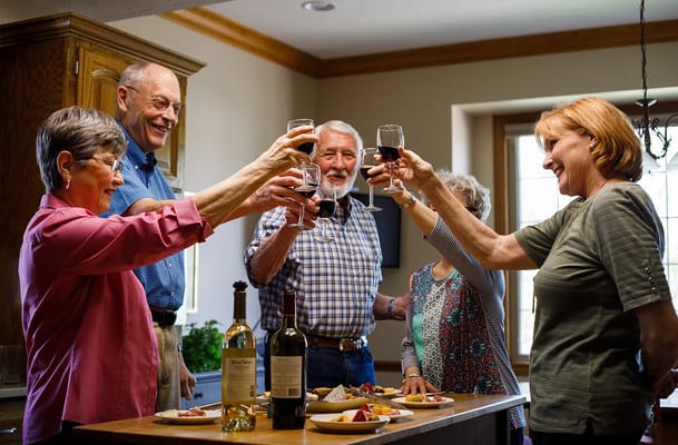 Residents and staff toasting with drinks in a living space