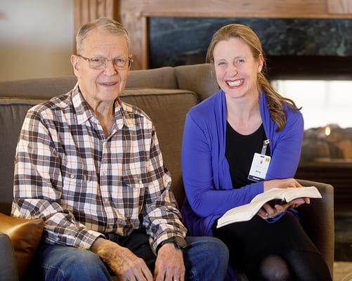 A resident and staff member smiling together indoors