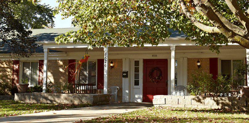 Front entrance of a senior living facility surrounded by trees