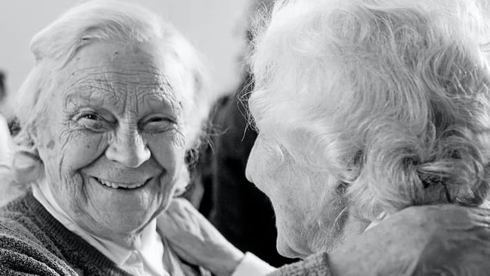 Two elderly women sharing a joyful moment together