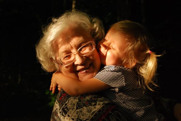A senior woman smiling with a child embracing her