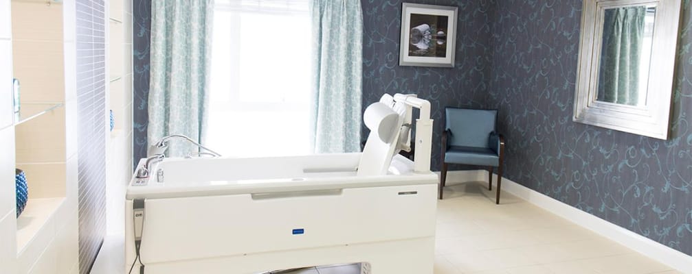 Brightly lit resident room with medical bed and chair
