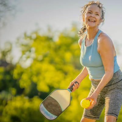 Senior woman playing pickleball outdoors