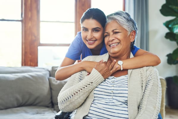A staff member and resident smiling together in a living room
