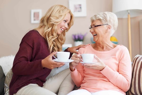 Two women laughing over tea in a cozy living room