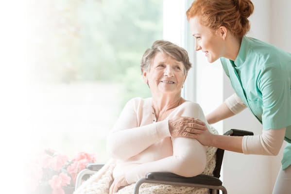 Caregiver assisting a resident in a bright indoor space
