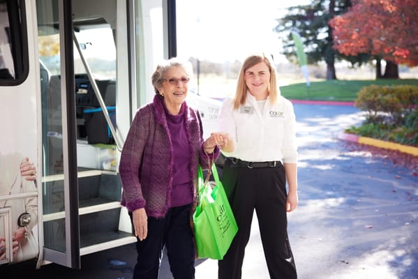 A staff member helping a resident near a facility vehicle