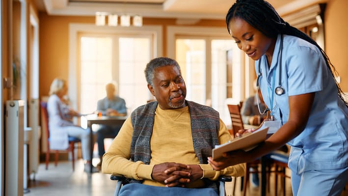 Caregiver assisting a resident in a bright common area