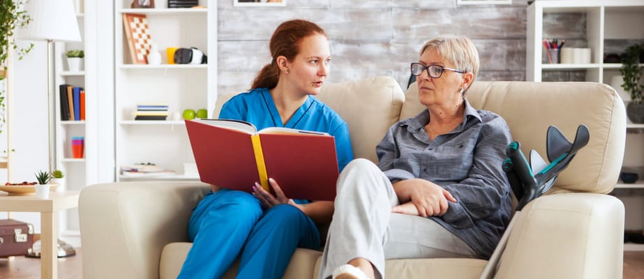 Staff member reading with resident in cozy common area
