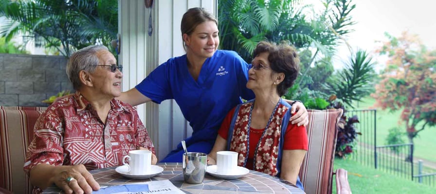 Caregiver interacting with two residents outdoors