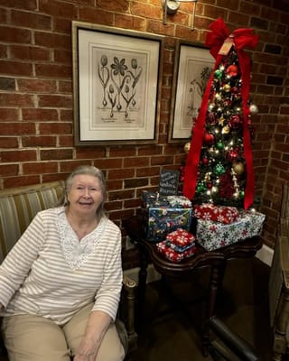 Resident beside a decorated Christmas tree with gifts
