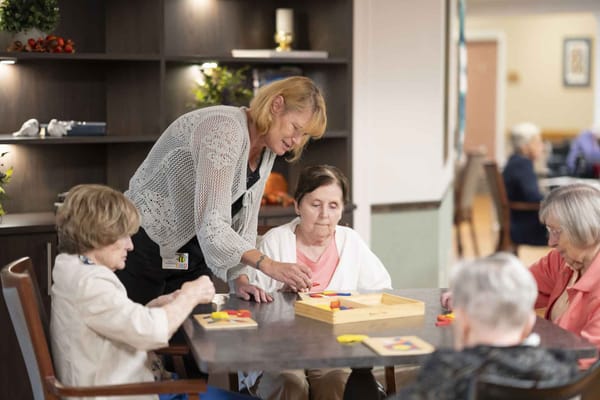 Residents engaged in a puzzle activity with staff