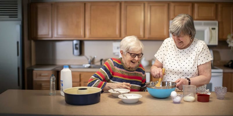 Two residents enjoying a cooking activity in the kitchen