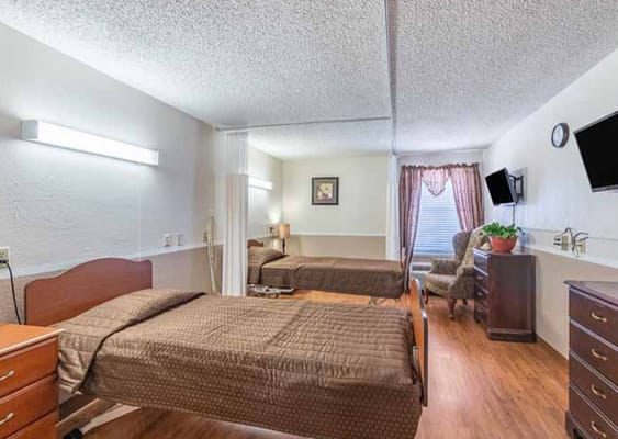 Spacious bedroom with two beds, dresser, and seating area.