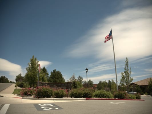 The entrance to Stone Valley Memory Care with a flag and landscaped flowers.