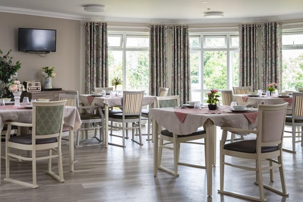 Bright dining room with tables set for residents
