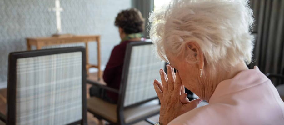 Two residents in a quiet activity space reflecting or praying