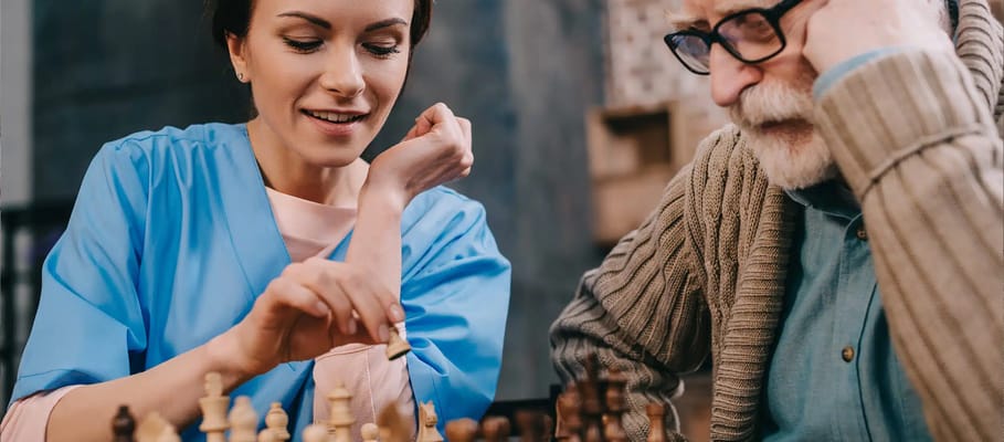 Caregiver playing chess with a senior resident