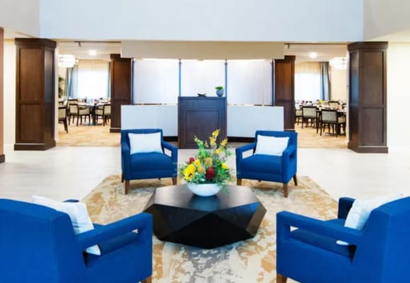 Bright common area with blue chairs and floral centerpiece