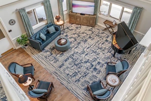 Aerial view of a cozy living room featuring a piano, sofa, and seating area.