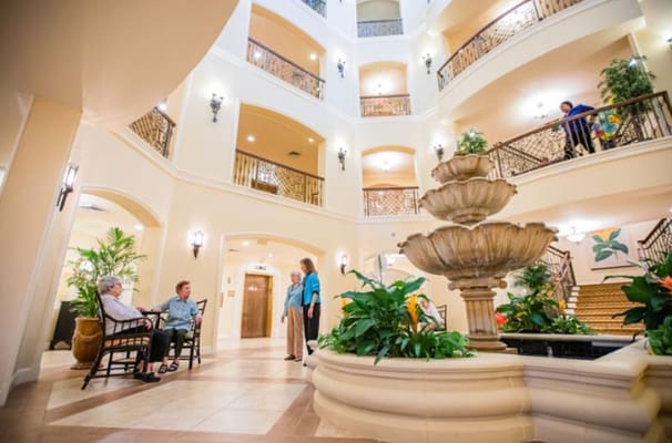 Seniors relaxing in the lobby with a central fountain and plants