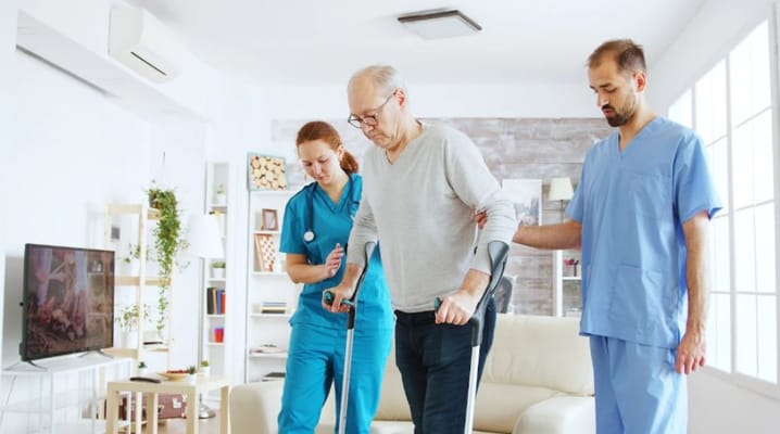 Healthcare staff assisting a resident in a living room