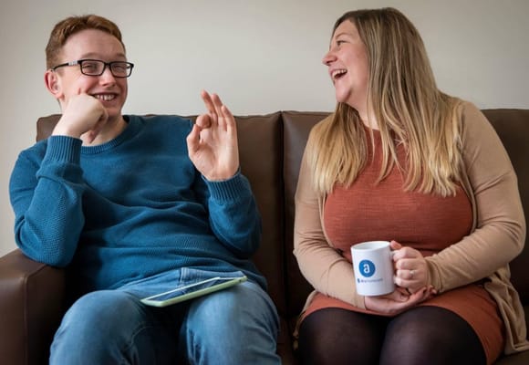 Two staff members laughing on a couch in a common area