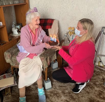 Resident celebrating 100th birthday with staff members