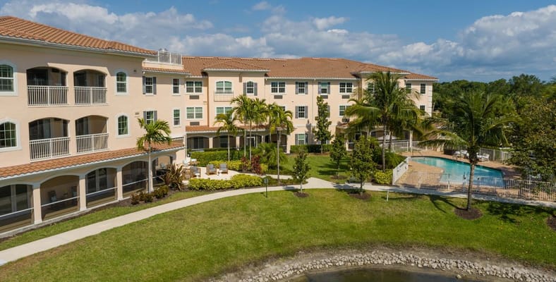 Aerial view of a senior living facility with gardens and a pool