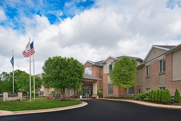 Front exterior of the assisted living facility with flags and landscaping