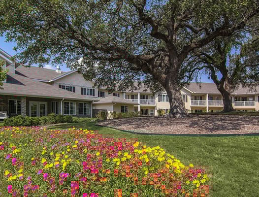 Exterior view of assisted living facility with flowers and trees