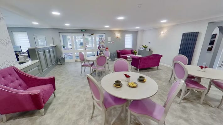 Bright common area with pink chairs and tables